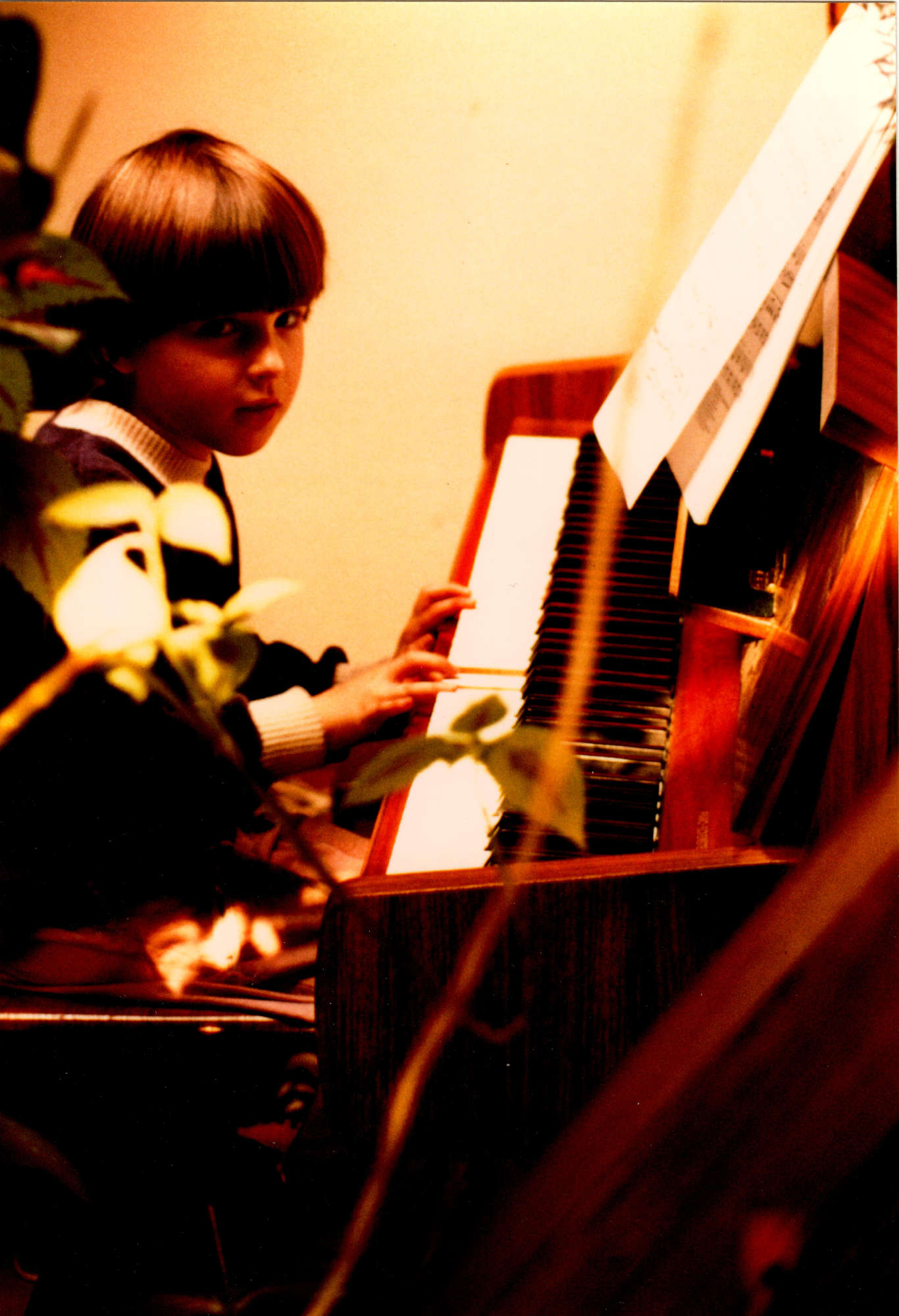 Die fünfjährige Martina sitzt mit Pagenschnitt am Klavier und schaut schüchtern lächelnd in die Kamera