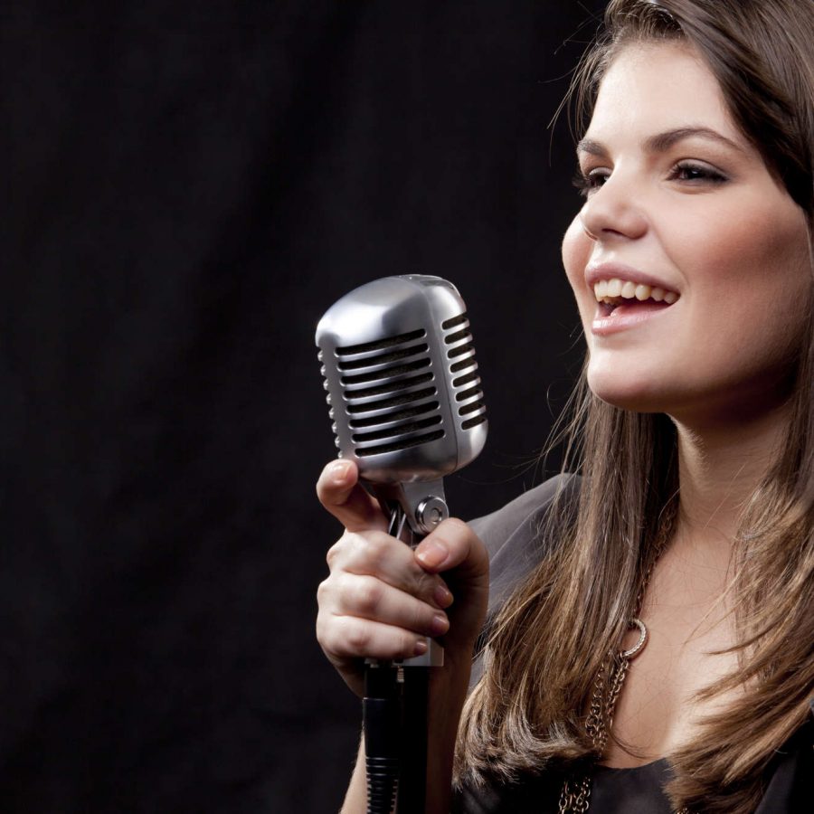 Sängerin mit langen Haaren am Mikrofon, die gerade eine Ansage macht